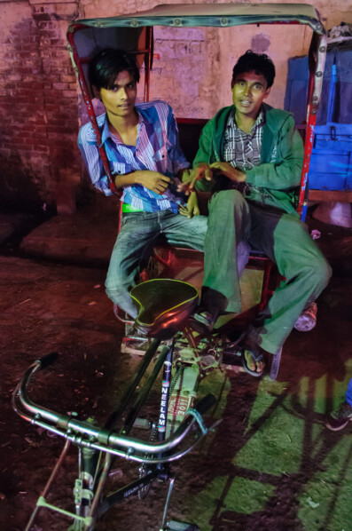 Two men sit in an Indian rickshaw.