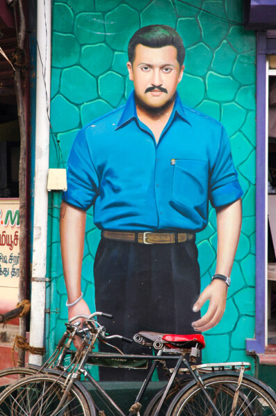 Bicycles are leaned against a portrait of a man in India