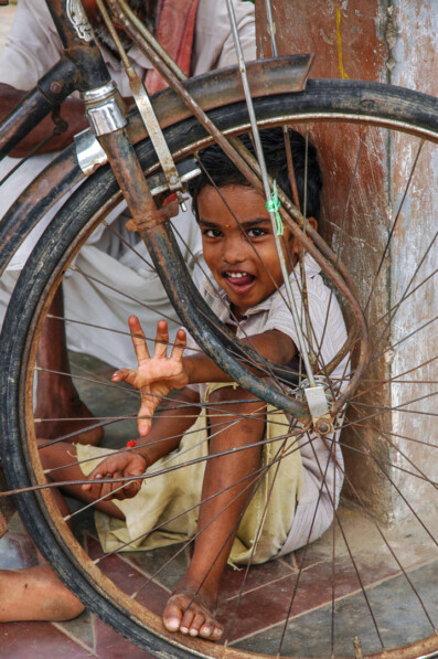 An Indian boy twangs bicycle spokes