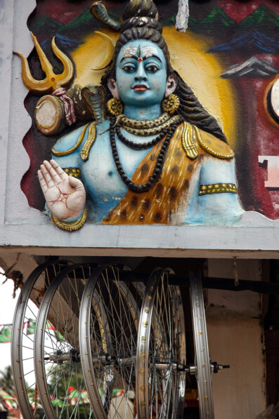The Indina God Shiva stands above hanging bicycle wheel rims