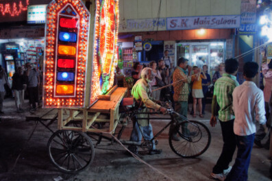 A lighted wedding rickshaw is being pushed during a wedding procession.