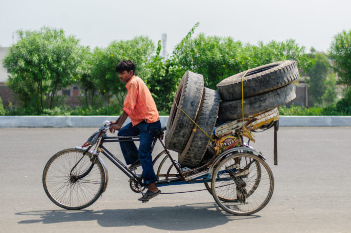 A rickshaw is loaded full of truck tires in North India.