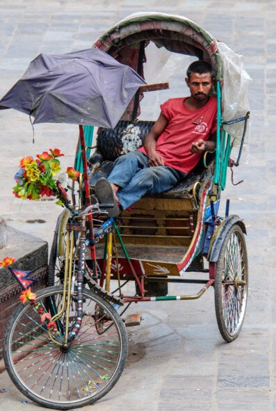A chauffeur sits in his rickshaw in Kathmandu, Nepal