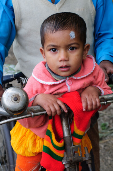 A father and his child sit on a bicycle in Bangladesh