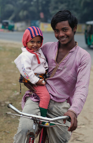 A boy and his little brother sit on a bicycle in Bangladesh