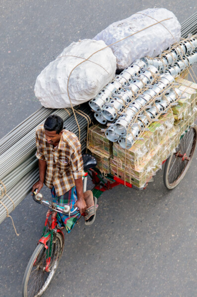 A Bike rickshaw heads to his destination with a full load.