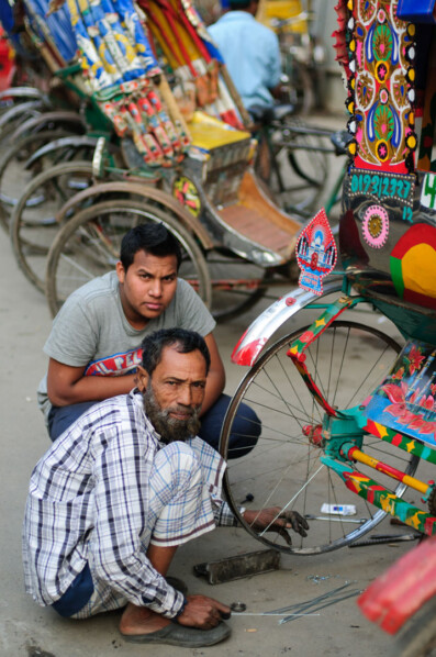 Rickshaw chauffeurs repair a rickshaw in Dhaka.