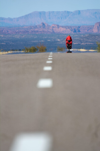 A touring cyclist heads towards colorful rock formations on Ruta 40 in Northern Argentina.