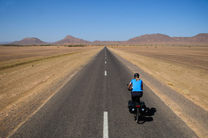 A blue cyclist heads towards the desert in Morocco