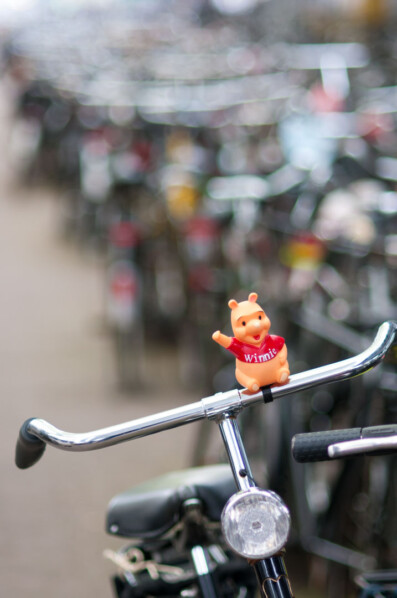 Winnie the Pooh stands on bicycle handlebars in Amsterdam.