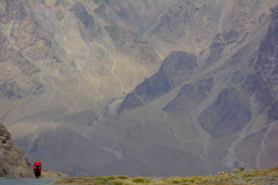 A small red bike heads down the Pamir highway.
