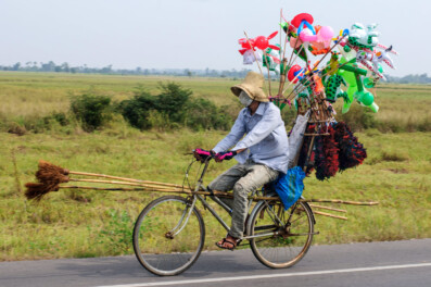 A cycling broom and balloon salesman in Cambodia.