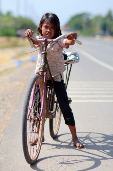 A small girl rides a bicycle in Cambodia.