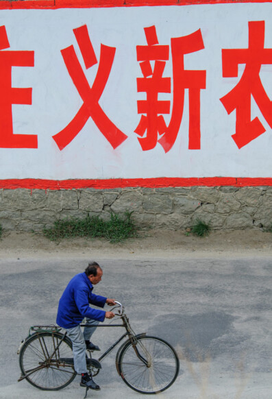 A man cycles past a sign in Chinese