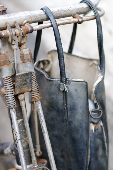 A handbag hangs from bicycle handlebars.