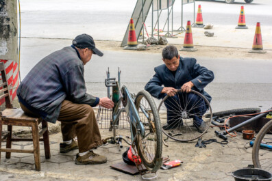 Two men fix a bicycle tire in China