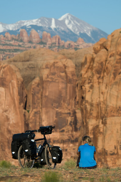 A touring cyclist gazes over rock formations near Canyonlands.