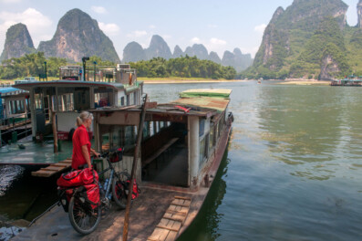 A touring cyclist takes a boat across a river near Guilin, China.