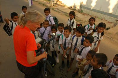 Indian school kids gather around a female touring cyclist.