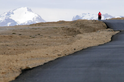 A littlre red cyclist heads across the More plains on the Leh Manali highway