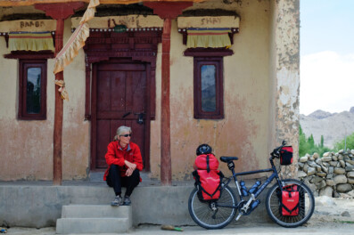 A cyclist sits on the steps of a Monastery in Ladkah.