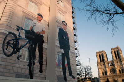 A policeman stands with a bicycle on a huge mural in Paris