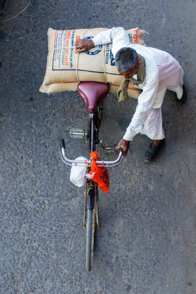 An elderly man pushes his overloaded bicycle in North India.