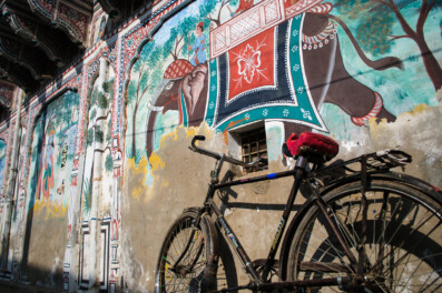 An Indian bike leans against a painted wall in the Shekhawati region of North India.