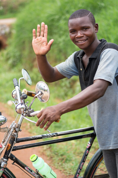 A Malawi bicycle taxi chauffeur waves his hand