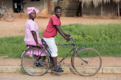 A Malawi boda boda bicycle taxi carries a fancy dressed lady on the back rack