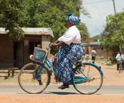 An african woman cycles home from the market