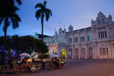 Penang city hall with rickshaws parked in front.