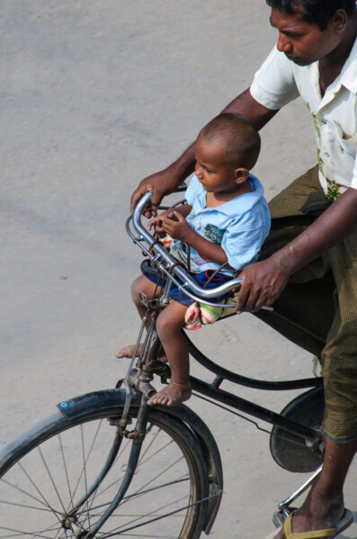 A father transports his son by bicycle in Myanmar