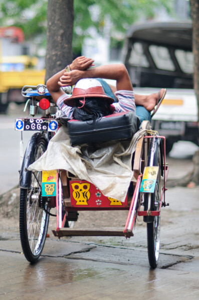 A rickshaw chauffeur takes a nap in his rickshaw in Myanmar.