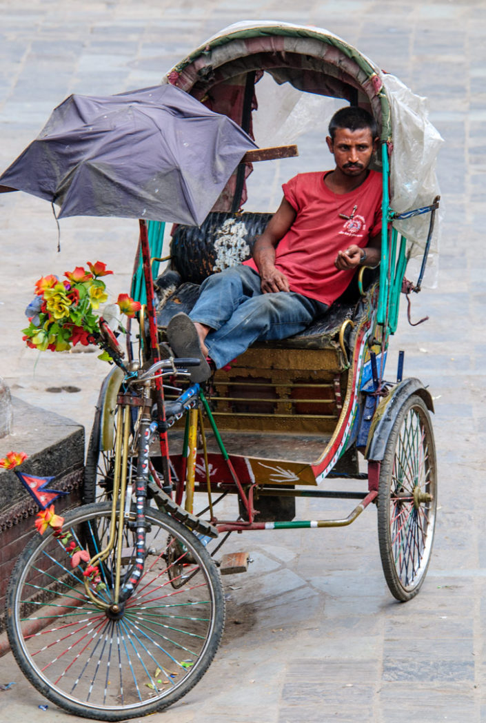 Bicycle culture - a Kathmandu chauffeur sits in his rickshaw while waiting for customers.