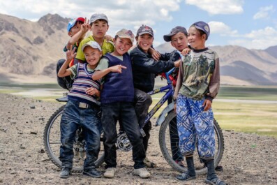 Tajikistan boys stand in front of a bicycle.