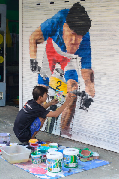 A Thai mand paints a bicycle on a garage door in Thailand