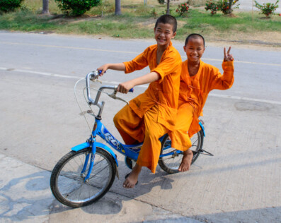 Two young monks ride a bike in Thailand.