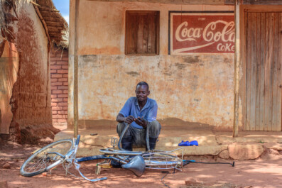 A Zambian man repairs a bicycle flat tire.
