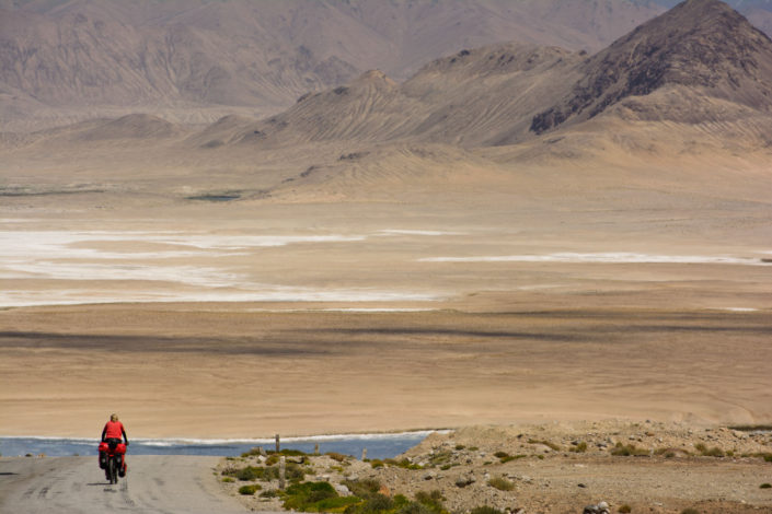Cycling through the desert landscape of the Pamir highway in Tajikistan.