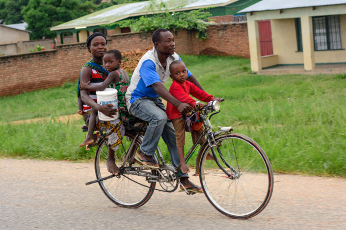 An African family sits on a single bicycle
