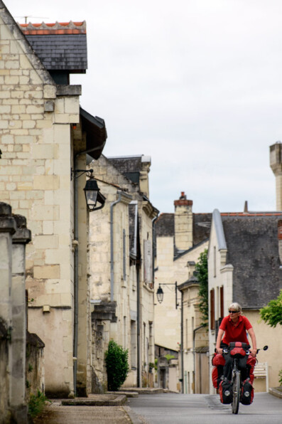 A cyclist rides through a small town in France.