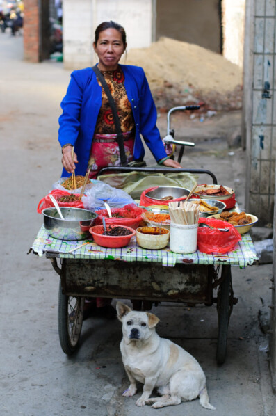 A lady stands behind a cargo bike -food stall in China