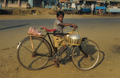 A boy in India holds a bicycle