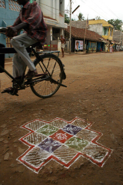 An Indian cyclist rides past a design on the ground