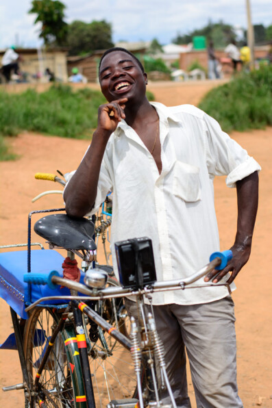 A smiling bicycle taxi chauffer stands next to his bike in Malawi, Africa