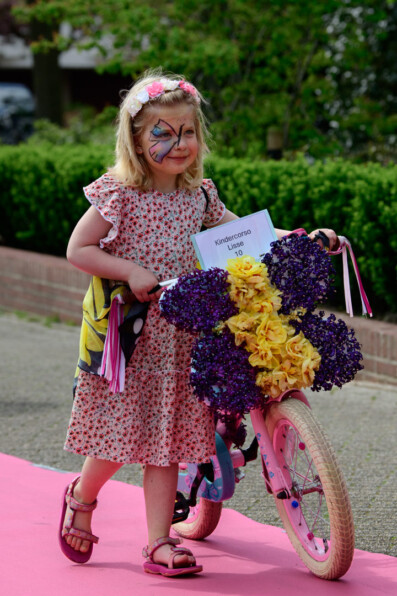 Young girl walks with her bike over a pink carpet during the kindercorso in Lisse, the Netherlands.